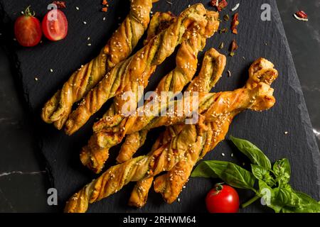 Bastoncini di pane con sesamo e pomodoro. Bastoncini di pane fatti in casa. Stuzzichini fatti in casa. Sfondo scuro, vista dall'alto, primo piano, flatlay Foto Stock