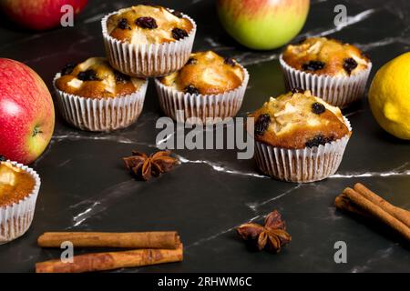 Muffin fatti in casa con mele, uva passa e bastoncini di cannella. Su uno sfondo scuro Foto Stock