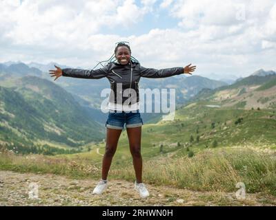 giovane donna che salta felice e si gode la natura nelle alpi italiane Foto Stock