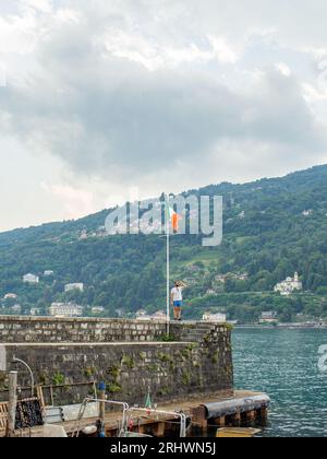 giovane che guarda una bandiera italiana in un porto italiano Foto Stock