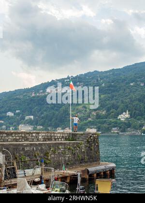 giovane che guarda una bandiera italiana in un porto italiano Foto Stock