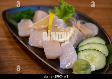 Sashimaci caldo o capesante serviti su piatto con limone Foto Stock