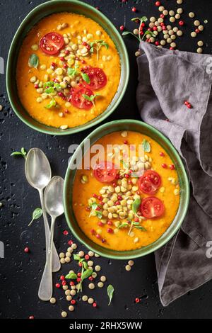 Deliziosa zuppa di lenticchie con panna e pomodori ciliegini. Zuppa gialla di lenticchie a base di verdure. Foto Stock