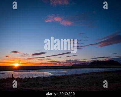 Il sole tramonta su un corpo d'acqua. Foto di un bellissimo tramonto su un sereno specchio d'acqua islandese Foto Stock
