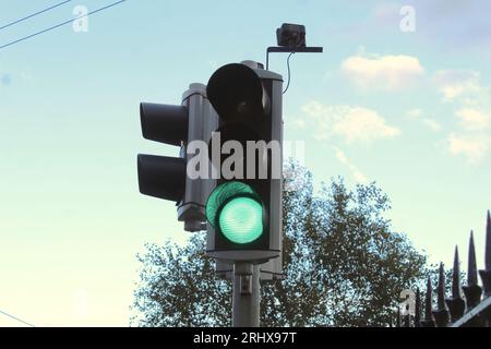 Una foto di un semaforo verde contro un cielo nuvoloso arancione. Foto Stock