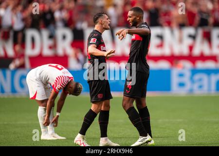 Leverkusen, Germania. 19 agosto 2023. Calcio: Bundesliga, Bayer Leverkusen - RB Leipzig, giorno 1, BayArena. Leverkusen's Granit Xhaka (centro) e Jonathan Tah si alzarono a cinque dopo la partita. A sinistra, Benjamin Henrichs di Lipsia. Credito: Marius Becker/dpa - NOTA IMPORTANTE: conformemente ai requisiti della DFL Deutsche Fußball Liga e della DFB Deutscher Fußball-Bund, è vietato utilizzare o far utilizzare fotografie scattate nello stadio e/o della partita sotto forma di immagini di sequenza e/o serie di foto simili a video./dpa/Alamy Live News Foto Stock