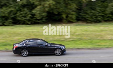 Milton Keynes, Regno Unito - 16 agosto 2023: 2014 auto Mercedes Benz C 200 nera che viaggia su una strada di campagna inglese. Foto Stock