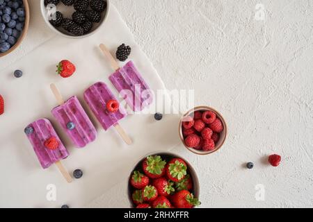 Vista dall'alto del gelato biologico a base di proteine vegane fatto in casa collocato su una superficie bianca vicino a ciotole con diversi tipi di frutta fresca Foto Stock