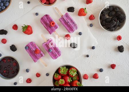 Vista dall'alto del gelato biologico a base di proteine vegane fatto in casa collocato su una superficie bianca vicino a ciotole con diversi tipi di frutta fresca Foto Stock