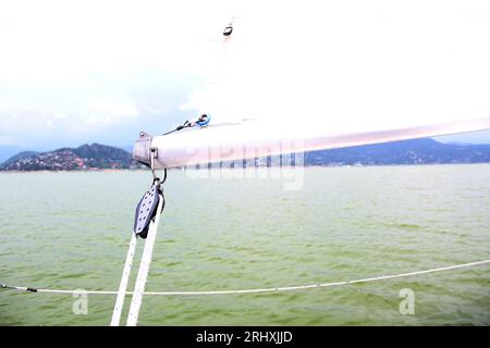 Parti di una barca a vela che naviga sul lago con vele fuori, prua, poppa, lamiera, albero, timone, paletta meteorologica Foto Stock