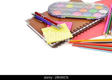 Acquerelli, quaderni e altri materiali scolastici isolati su sfondo bianco. Con spazio libero per il testo. Foto Stock