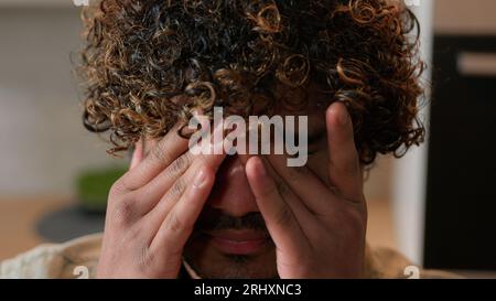 Primo piano Indiano malato stanco sonnolento uomo con capelli ricci che sfregano occhi asciutti uomo d'affari malato stanco arabo al chiuso soffre di affaticamento degli occhi disagio Foto Stock