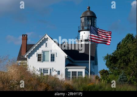 La bandiera americana ondeggia davanti al faro di Cape Elizabeth nel Maine in una ventosa giornata estiva. Foto Stock