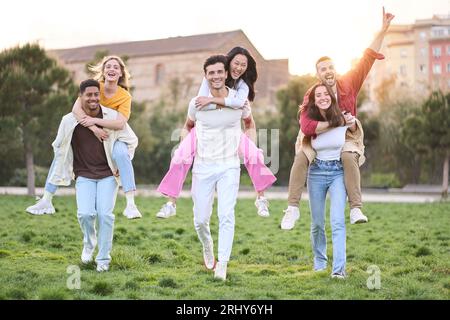 Un gruppo di divertenti coppie di amici che si aggirano nel parco nelle soleggiate giornate primaverili. Tre coppie di allegri. Foto Stock