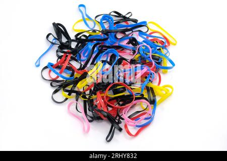 Elastici in silicone sottili su sfondo bianco. Un set di piccole fascette per capelli in silicone. Fasce elastiche per trecce di diversi colori. Multicolore Foto Stock