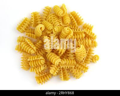 Vista dall'alto sulla pasta di grano duro. Pasta a spirale su sfondo bianco. Primi piani della pasta riccia secca. Sfondo di macaroni non bolliti giallo. italia cruda Foto Stock