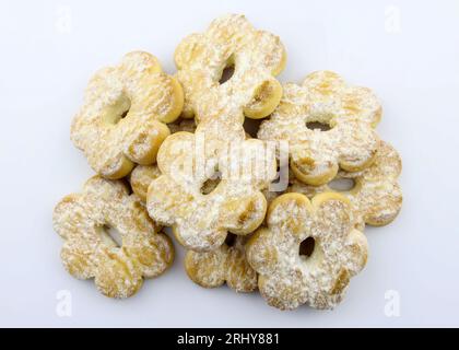 Biscotti a forma di fiore cosparsi di zucchero in polvere. Primi piani con gustosi biscotti fatti in casa su sfondo bianco. Confetteria per il tè. Foto Stock