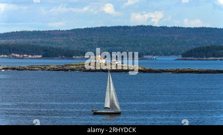 Egg Rock Light - Telephoto shot of a small sailboat passing in front of Egg Rock Light Station on a sunny Autumn morning, Mount Desert  Island, Maine. Foto Stock