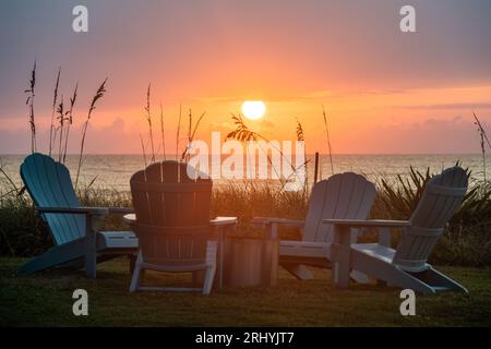 Vista colorata all'alba delle sedie Adirondack intorno a un caminetto in una casa sulla spiaggia di Ponte Vedra Beach, Florida, appena a nord di St. Augustine. Foto Stock