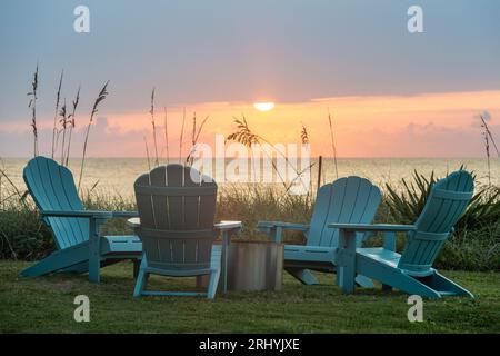 Vista colorata all'alba delle sedie Adirondack intorno a un caminetto in una casa sulla spiaggia di Ponte Vedra Beach, Florida, appena a nord di St. Augustine. Foto Stock