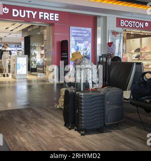 Uomo di mezza età che usa il suo iPhone in attesa di un volo nell'area del gate di partenza internazionale all'aeroporto Logan di Boston ma, Stati Uniti. Foto Stock