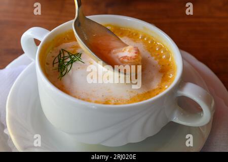 Krabbensuppe Busumer, zuppa alla busom con granchi del Mare del Nord o gamberetti marroni su un cucchiaio in una ciotola bianca Foto Stock