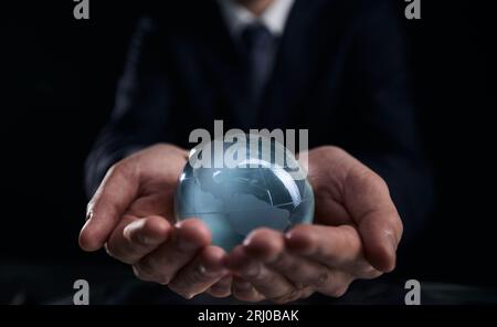 un uomo d'affari tiene il globo di vetro con i continenti in mano Foto Stock