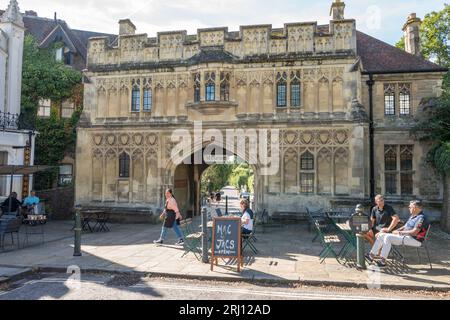 People relaxing at an outdoor cafe in front of the Great Malvern Priory Gate House or Abbey Gate house now a museum on a sunny morning. Stock Photo