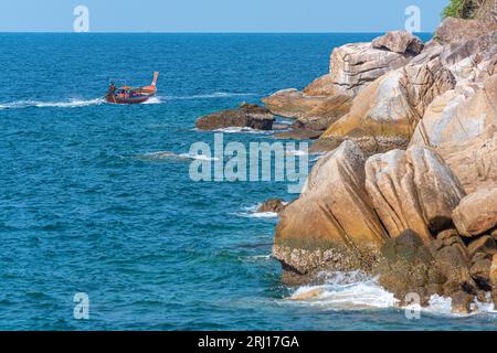 Viaggia su una barca a coda lunga lungo la costa rocciosa dell'isola di Ko Lipe, Thailandia Foto Stock