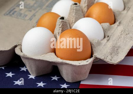 Cartone di uova bianche e marroni sulla bandiera degli Stati Uniti d'America. Concetto di allevamento avicolo, agricoltura e produzione di uova Foto Stock