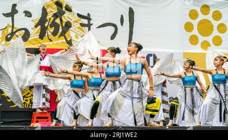 Squadra di danza giapponese Yosakoi con costumi d'argento e blu su un palco all'aperto che balla all'annuale festival Kumamoto Kyusyu Gassai. Foto Stock