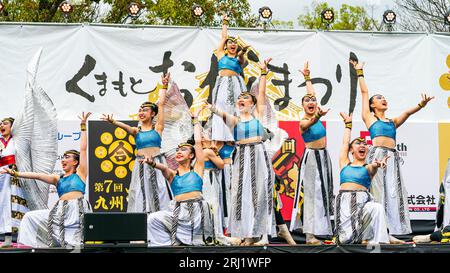 Squadra di danza giapponese Yosakoi con costumi d'argento e blu su un palco all'aperto che balla all'annuale festival Kumamoto Kyusyu Gassai. Foto Stock