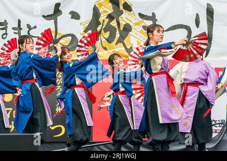 Ragazze giapponesi adolescenti squadra di danza Yosakoi in tuniche yukata e tenendo i fan su un palco all'aperto che balla al festival annuale di Kumamoto Kyusyu Gassai Foto Stock