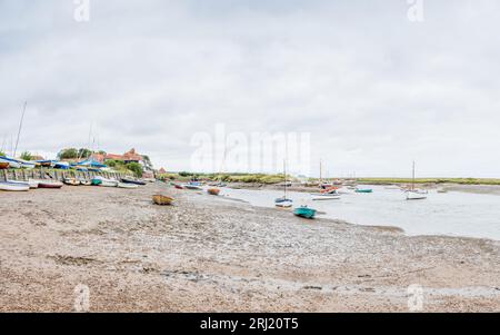 Un panorama multi immagine di barche viste durante la bassa marea a Burnham Overy Staithe sulla costa del Norfolk settentrionale visto nell'agosto 2023. Foto Stock