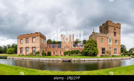 Un panorama multi immagine di una barca ormeggiata da gradini nel fossato che circonda Oxburgh Hall a Norfolk visto nell'agosto 2023. Foto Stock