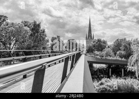 Lunghi corrimano e tavole di legno sul ponte Jarrold conducono verso la cattedrale di Norwich, raffigurata nell'agosto 2023 sopra il fiume Wensum. Foto Stock