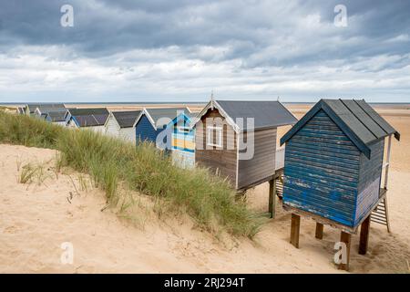 Affacciato sulle rustiche e colorate capanne sulla spiaggia che fiancheggiano la spiaggia a Wells, accanto al Mare, sulla costa del Norfolk settentrionale. Foto Stock