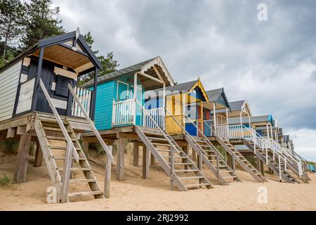 Rifugi sulla spiaggia a Wells, accanto al mare, sulla costa del Norfolk settentrionale, raffigurati sopra la spiaggia di sabbia dorata su palafitte di legno per proteggerli dalle alte maree. Foto Stock