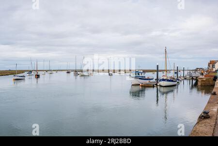 Vari tipi e dimensioni di barche raffigurate durante l'alta marea sulle acque calme di Wells vicino al porto marittimo visto nell'agosto 2023 sulla costa del Norfolk settentrionale Foto Stock