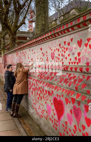 Una signora scrive sul "National Covid Memorial Wall", un murale pubblico per commemorare le vittime della pandemia di COVID-19 nel Regno Unito. Allungamento Foto Stock