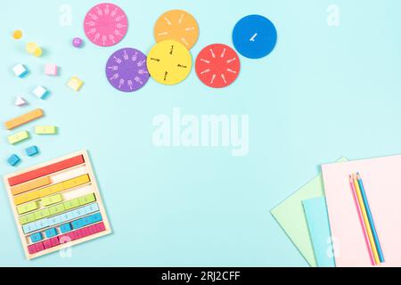 Educazione, matematica concetto di apprendimento. Forniture scolastiche e colorate frazioni matematiche, cubi su sfondo azzurro. Vista dall'alto, spazio di copia Foto Stock