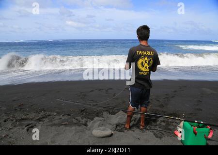 pêche à la ligne sur la plage de Sable noir volcanique de Papara à Tahiti en Polynésie francaise. Cette plage de Taharuu est connue pour ses belles va Foto Stock