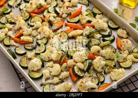 Varie verdure arrostite su teglia, cavolfiore, zucchine e carote con erbe aromatiche, contorno Foto Stock