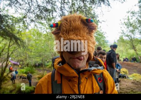 Uomo che tira una faccia divertente con un elegante cappello da mucca delle Highland Foto Stock