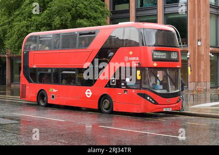 Londra, Regno Unito - 30 luglio 2023; autobus ibrido a due piani rosso di arriva sulla strada bagnata sotto la pioggia Foto Stock