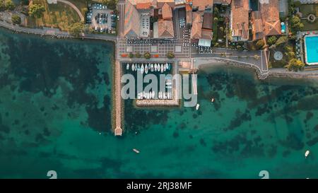 Vista aerea delle pittoresche acque turchesi del Porto di Cisano a Bardolino, Italia, sulle rive del Lago di Garda Foto Stock