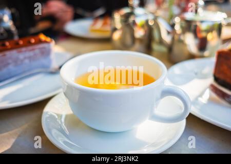 Tazza di tè sul tavolo. Bevanda calda con dessert in cucina. Tazza di tè alle erbe. Tè alla camomilla in una tazza bianca. Colazione mattutina. Selettivo Foto Stock