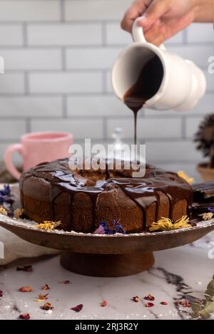 Il budino di cioccolata calda fuso viene versato su una torta al cioccolato come glassa Foto Stock