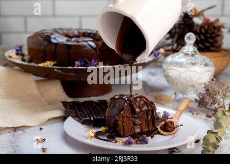 Il budino di cioccolata calda fuso viene versato su una torta al cioccolato come glassa Foto Stock