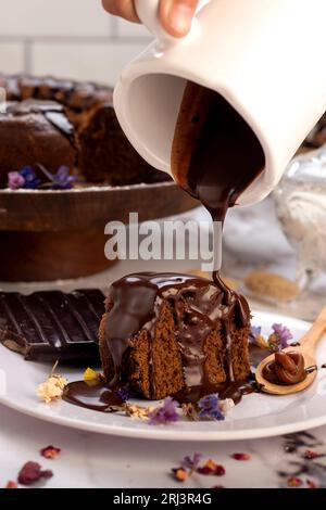 Il budino di cioccolata calda fuso viene versato su una torta al cioccolato come glassa Foto Stock
